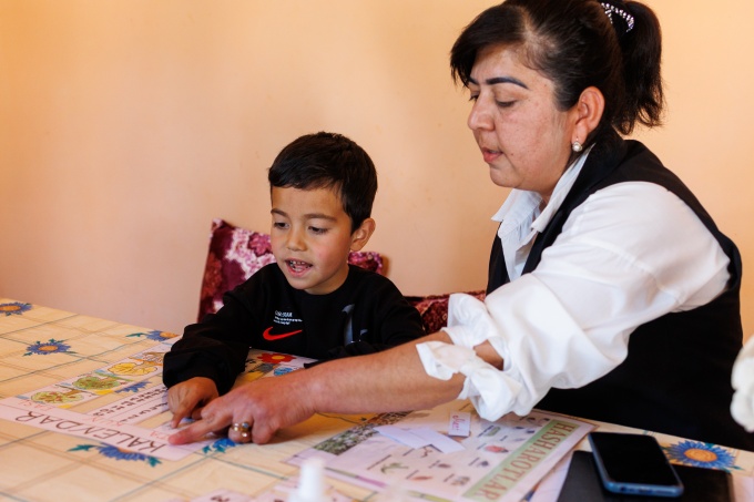 Hondamir learning through play-based activities with his teacher, Aziza. Credit: GPE/Federico Scoppa